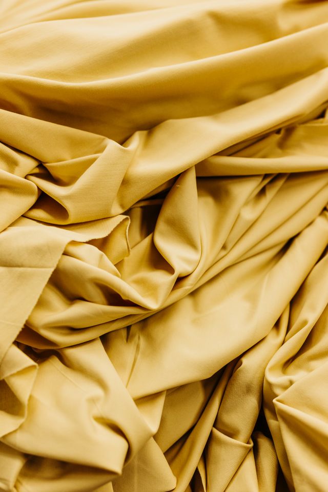 Close-up of crumpled golden fabric, highlighting its soft and luxurious texture.
