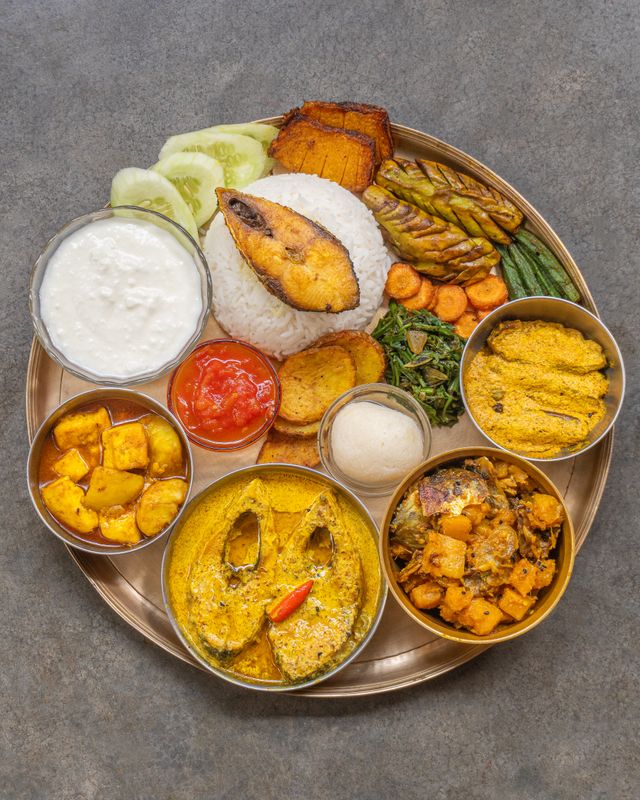 Overhead shot of a traditional Indian thali featuring rice, fish curry, and various vegetarian side dishes.